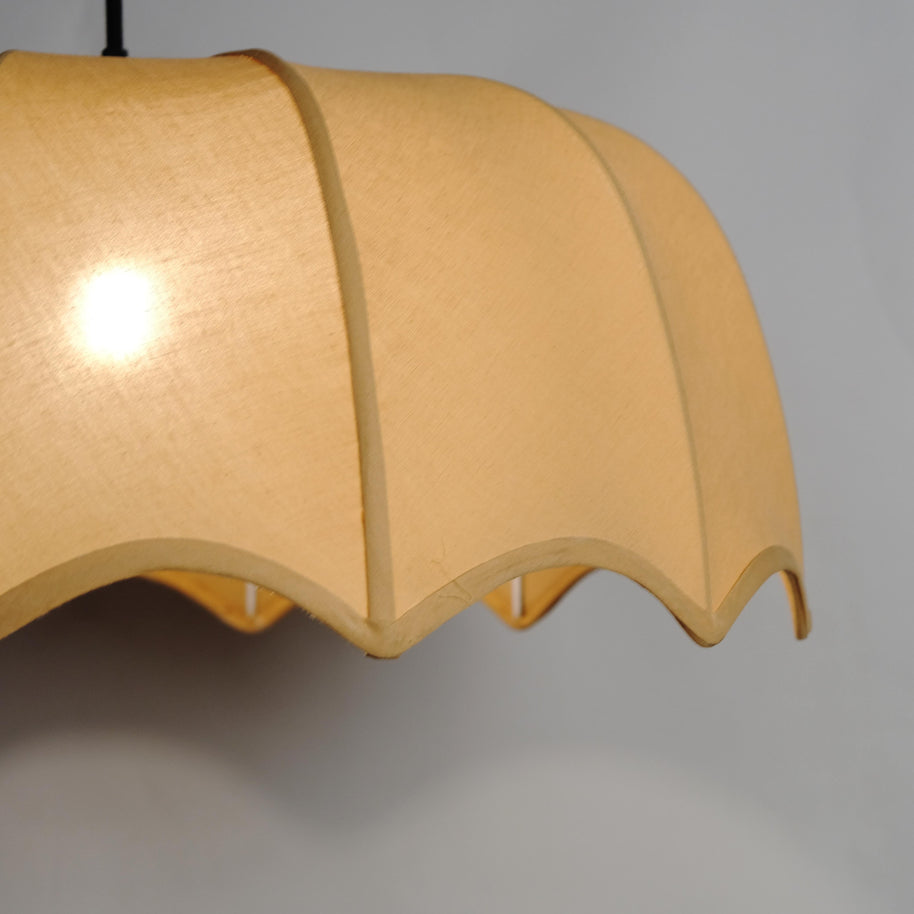 Close-up of a beige fabric pendant light with a unique wavy design, blending modern and classic styles