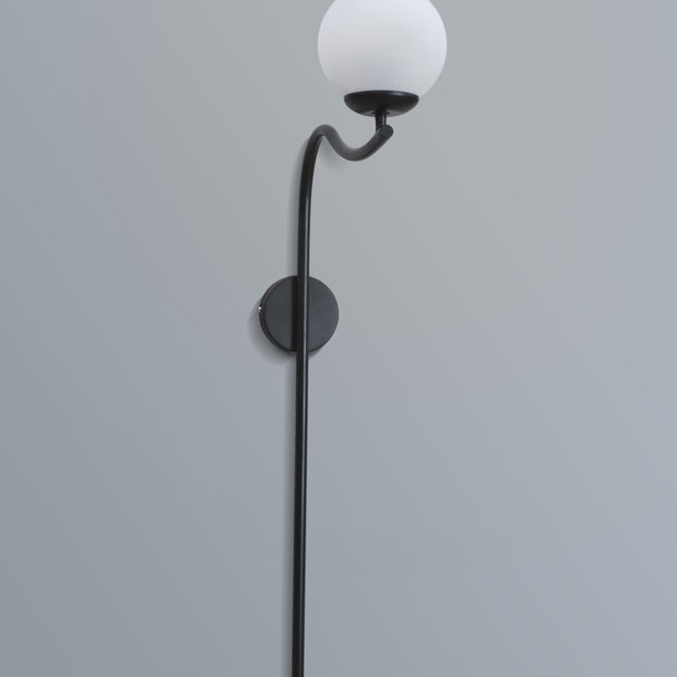 Elegant arched wall lamp featuring a black metal frame and a soft-glow white lampshade, enhancing a stylish interior.