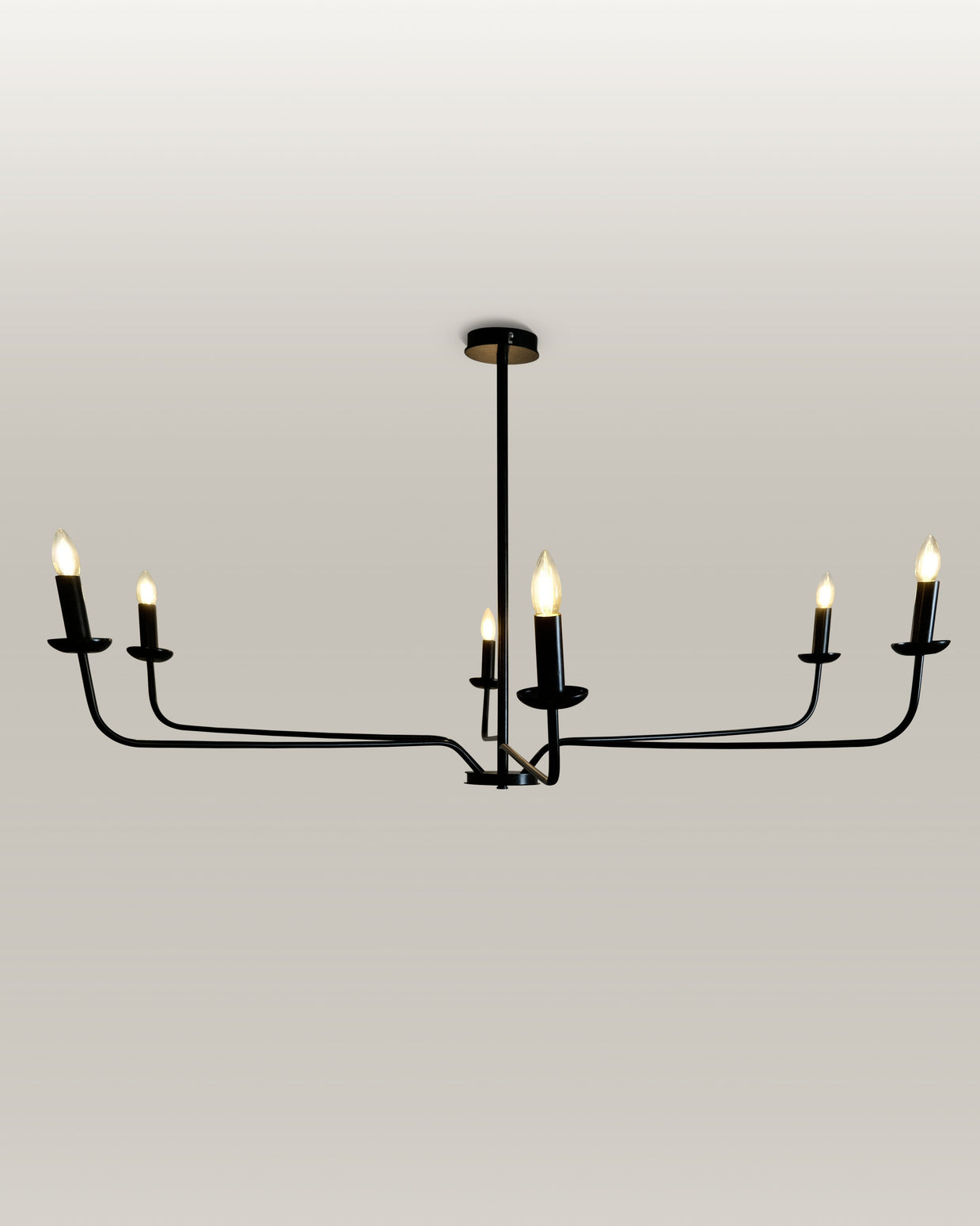 Elegant black metal chandelier with candle flame light bulbs, providing a warm glow in an entryway