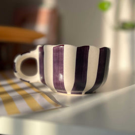 Striped ceramic cup on a table with a blurred background. purple, blackcurrant color. 
