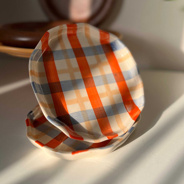Stack of checkered ceramic plates on a light surface with a blurred background