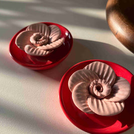 Decorative items with red bases and metallic top designs on a light background