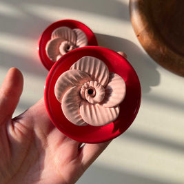 Hand holding a red decorative item with a white background
