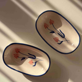 Two oval ceramic dishes with floral designs on a white surface.