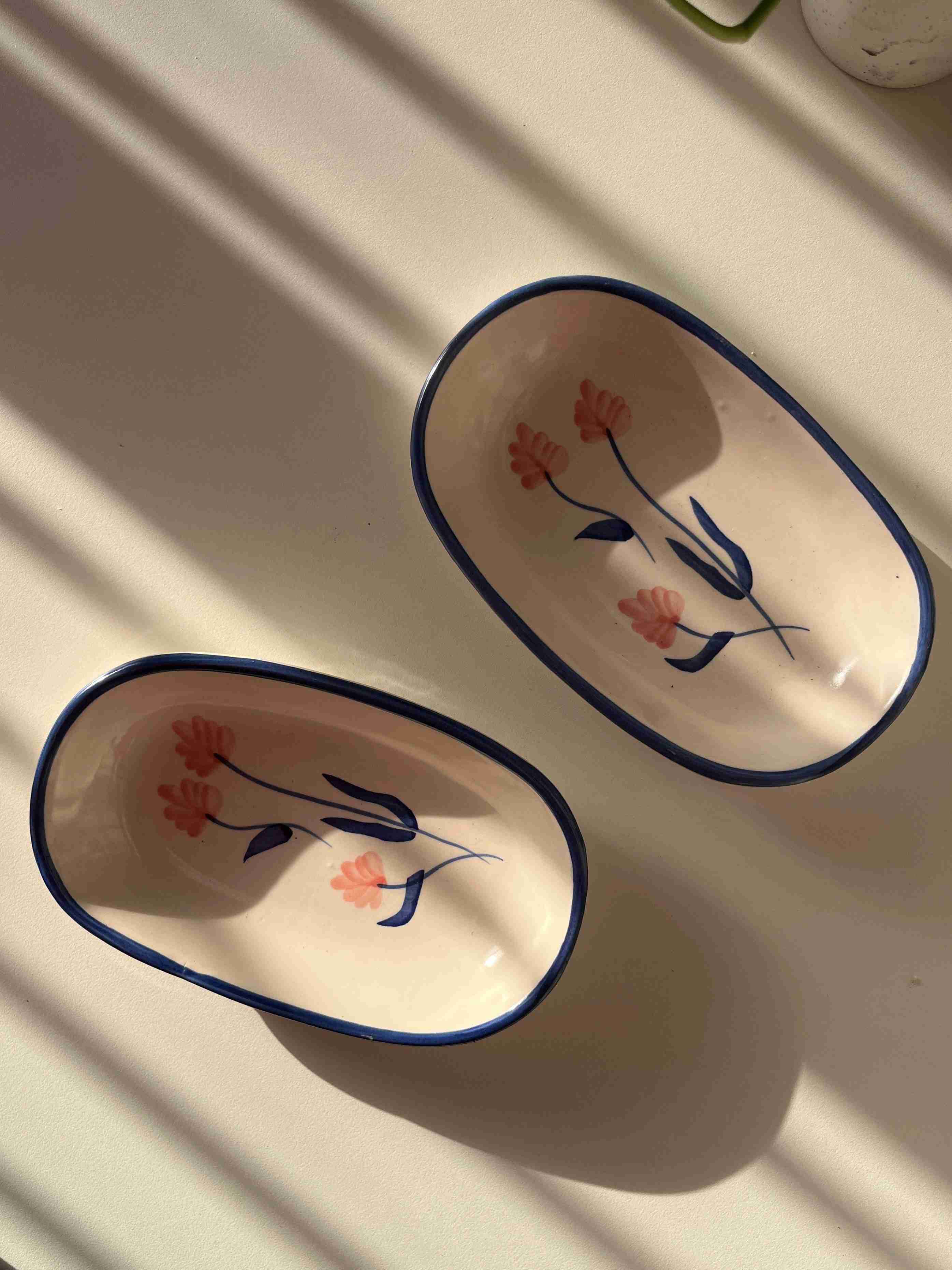 Two oval ceramic dishes with floral designs on a white surface.
