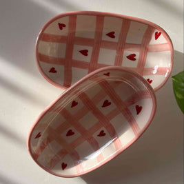 Two small ceramic dishes with heart patterns on a white surface.