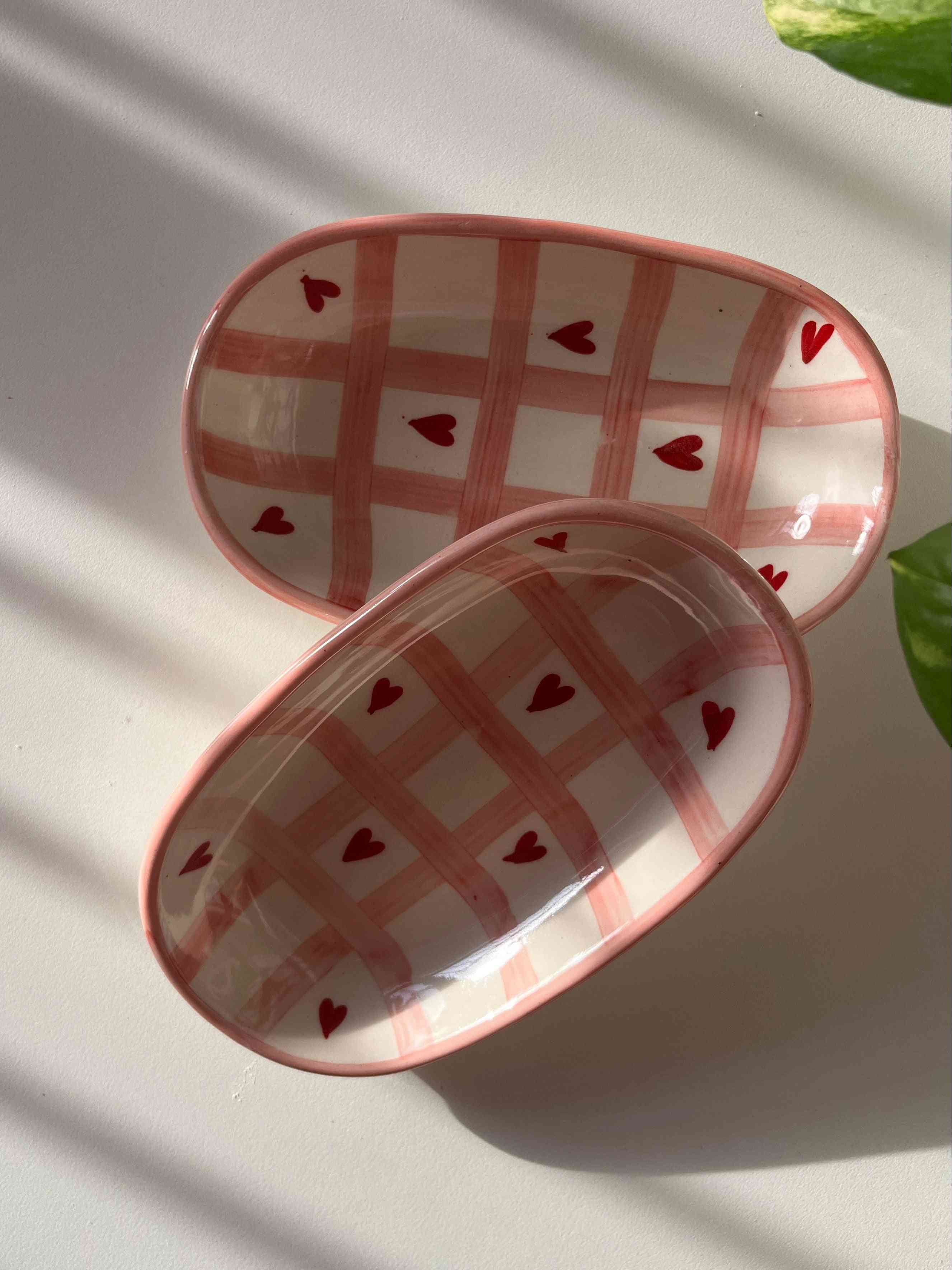 Two small ceramic dishes with heart patterns on a white surface.