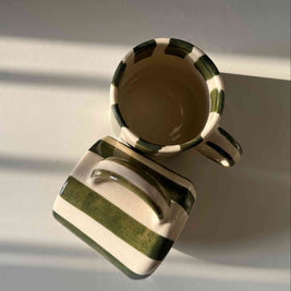green stripes ceramic mugs on a reflective surface with a blurred background