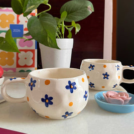 blue flowers with yellow 3D dot in the middle on a abstract white cramic cup