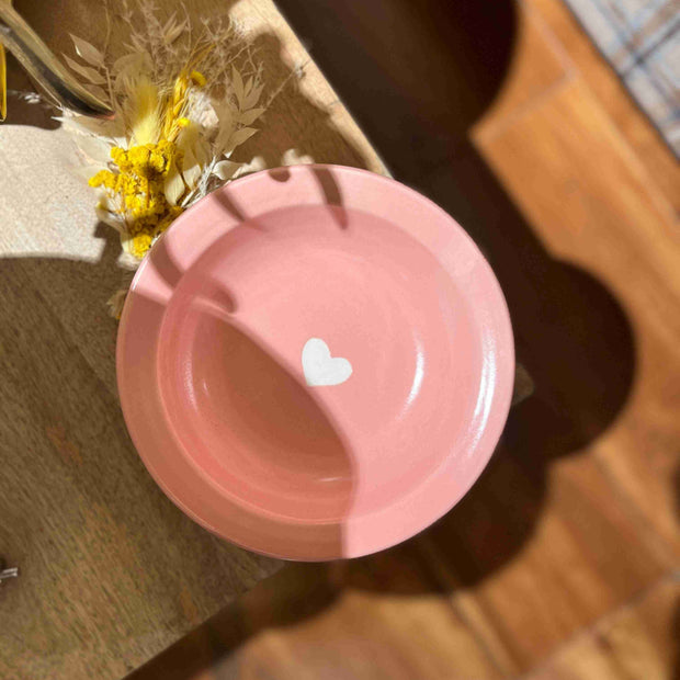 Pink plate with a white heart on a wooden surface