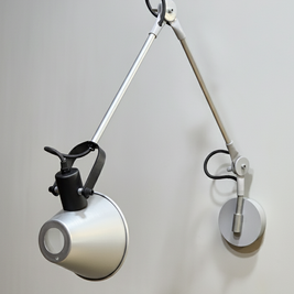 Minimal wall-mounted lamp with a movable arm, allowing precise control of light direction.