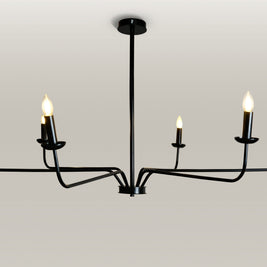 Minimalist chandelier featuring six black metal arms and candle flame light bulbs, illuminating a contemporary dining area.