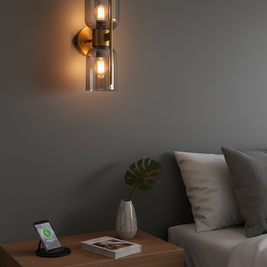 Modern wall sconce on a gray wall above a wooden nightstand with a smartphone and plant.
