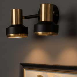 Modern wall sconce with gold and black finish on a dark wall.