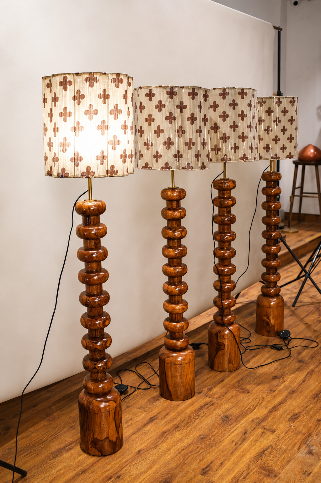 Set of wooden floor lamps with patterned lampshades on a wooden floor.