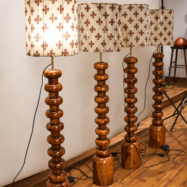 Set of wooden floor lamps with patterned lampshades on a wooden floor.