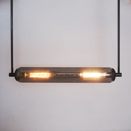 This modern lighting solution features an elongated glass tube encasing two glowing filament bulbs