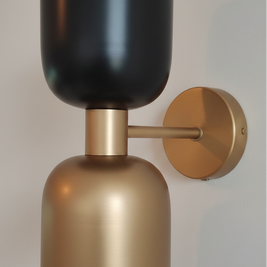 Wall-mounted light fixture with black and gold design on a neutral background