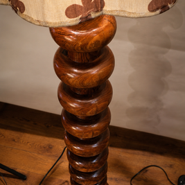 Wooden lamp with floral-patterned shade on a wooden floor.
