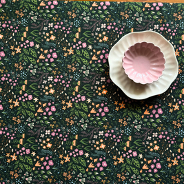 Decorative dining table cover with fantasy-inspired design with a pink daisy bowl and white plate on top