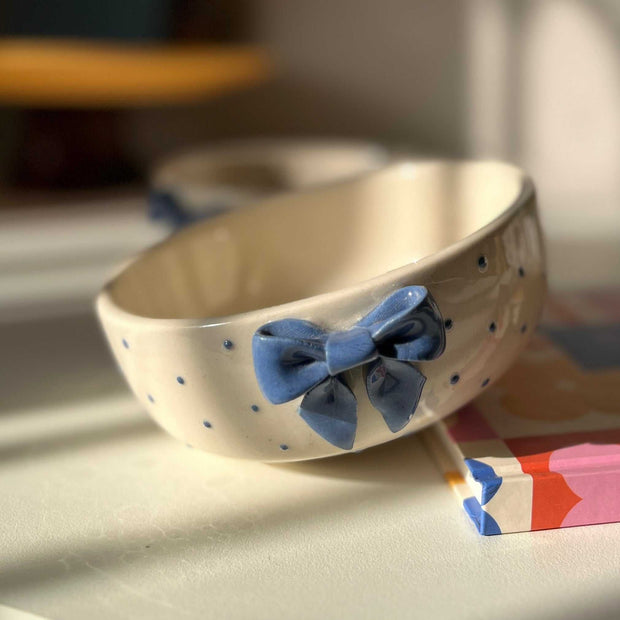 Ceramic bowl with a blue bow on a table with a blurred background