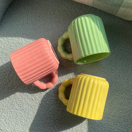 Close-up of the fluted texture and chunky handle design of ceramic mugs.