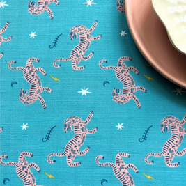 Blue fabric with pink tiger pattern and a plate on a blue background