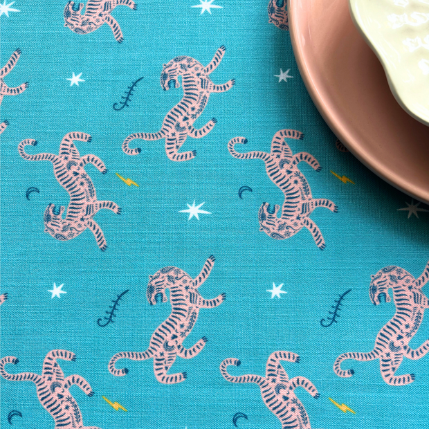 Blue fabric with pink tiger pattern and a plate on a blue background