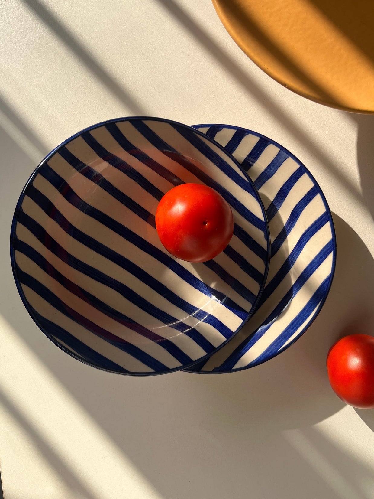 Wide shallow ceramic plate with deep blue hand-painted stripes