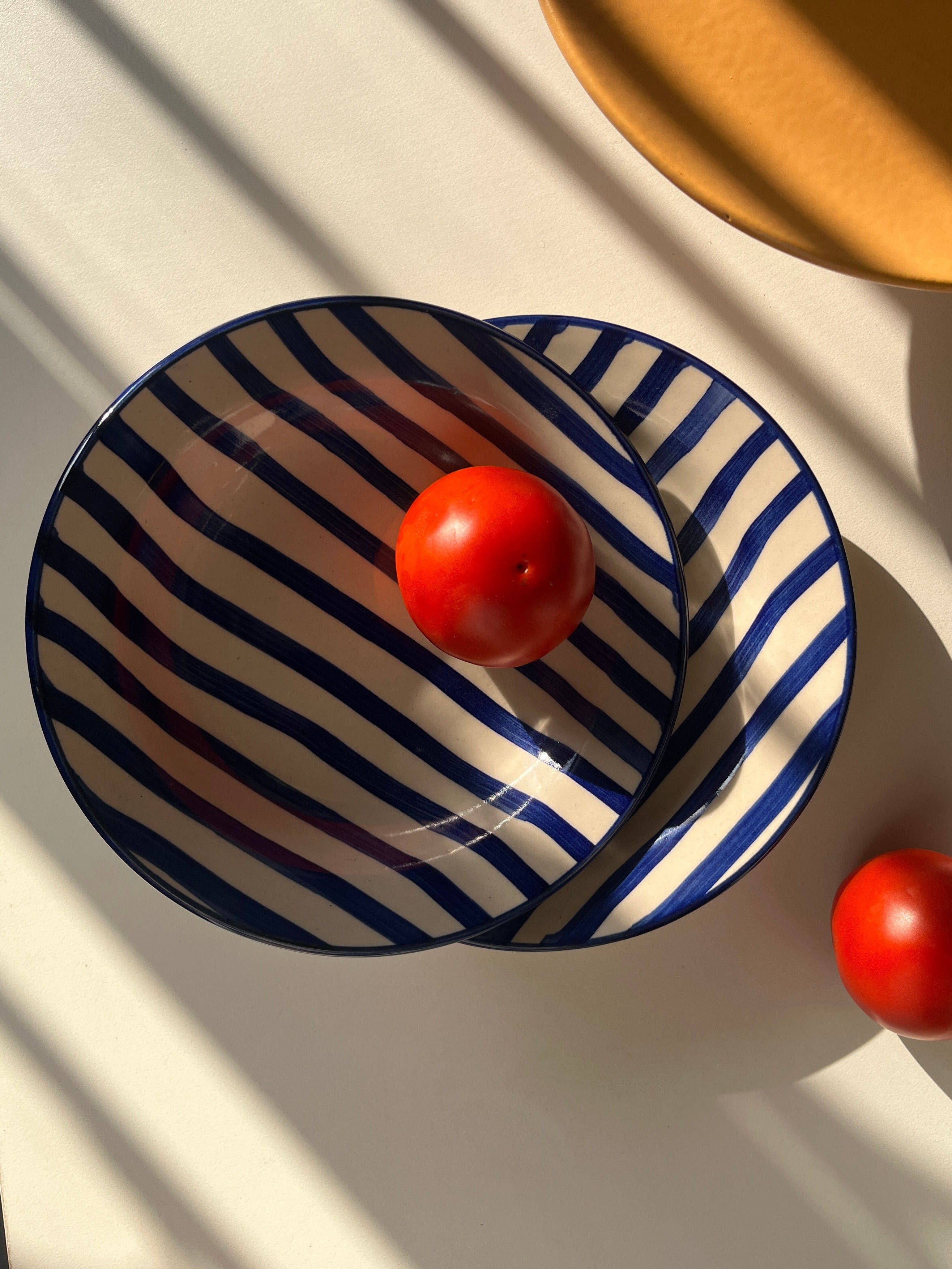 Wide shallow ceramic plate with deep blue hand-painted stripes