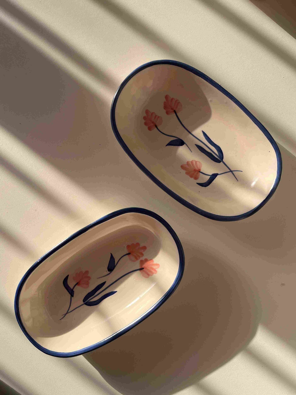 Two ceramic trays with floral designs on a white surface