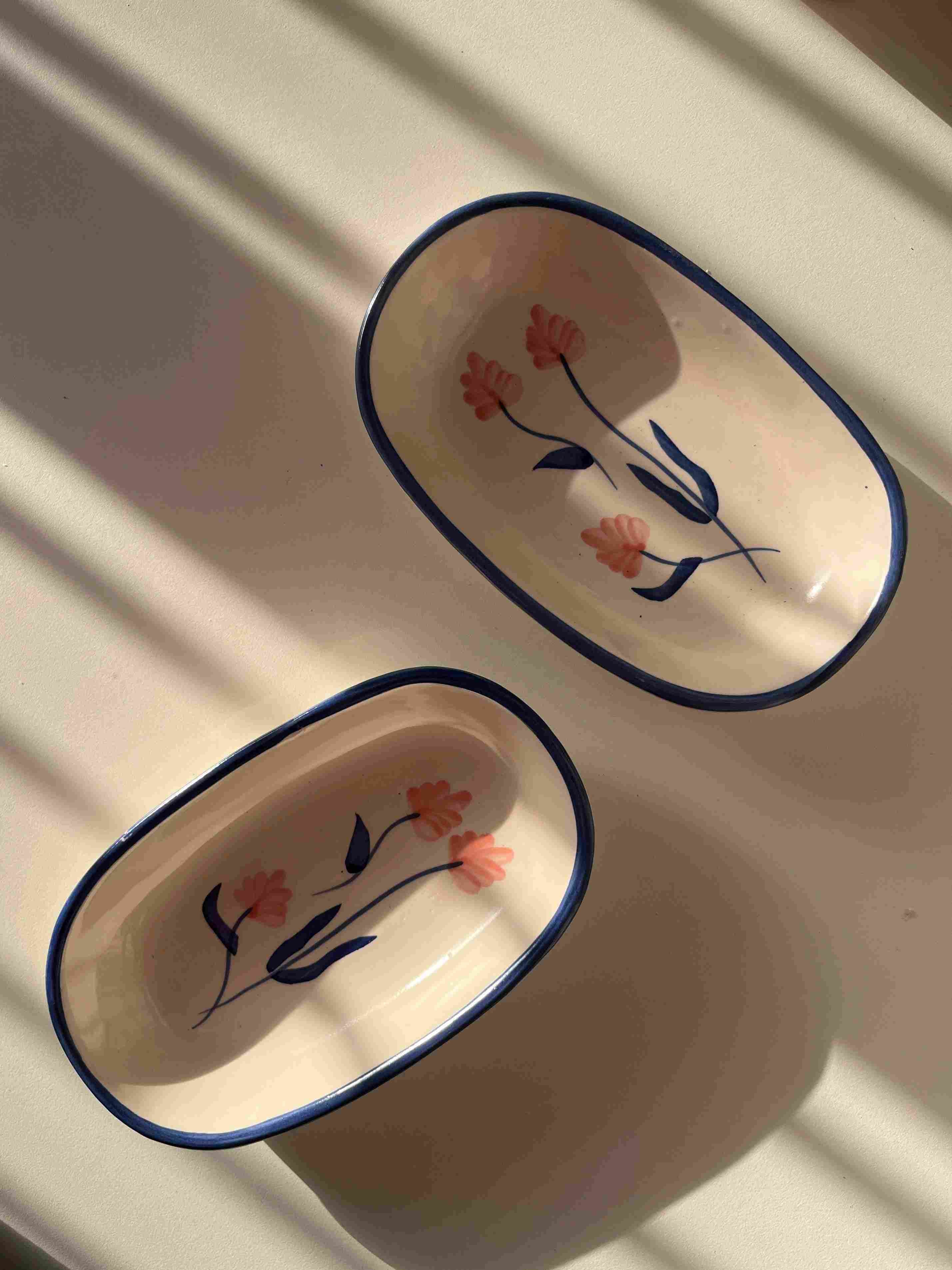 Two ceramic trays with floral designs on a white surface