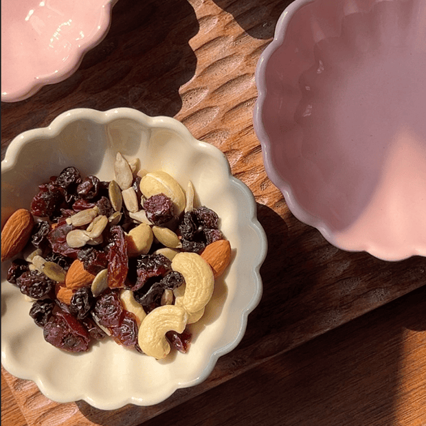 Daisy ceramic bowl available in soft pink and egg white with dried fruit under the sunlight