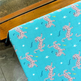 Blue slub linen tablecloth with white tiger pattern on a wooden table