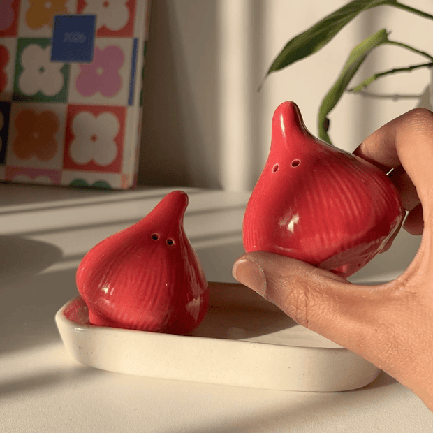 2 Red salt and pepper shakers in shape of onions with a red ceramic trinket tray along as a base.