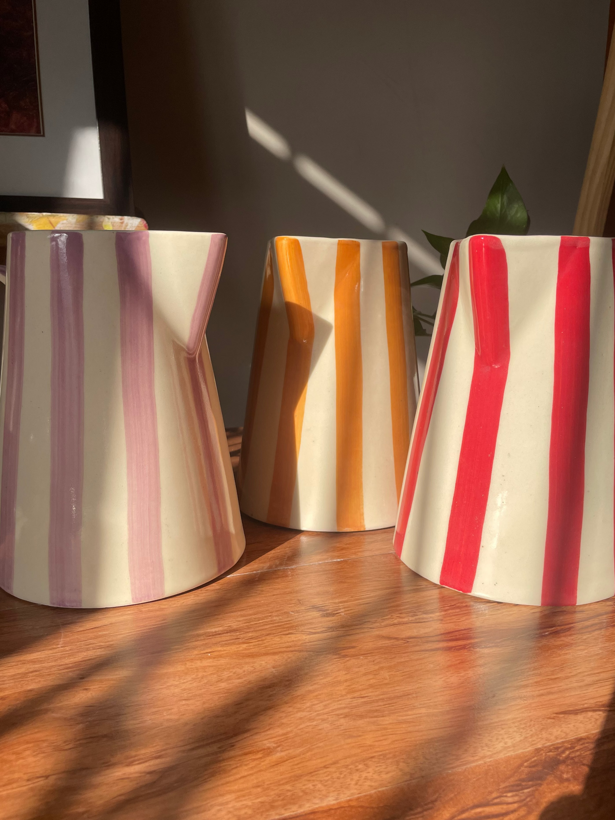 Three striped ceramic vases on a wooden surface with a blurred background
