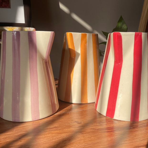 Three striped ceramic vases on a wooden surface with a blurred background