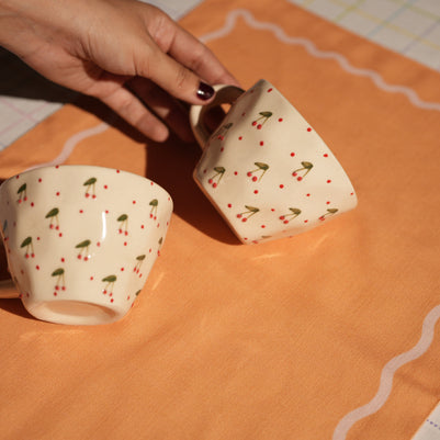 Close-up of cherry detailing on ceramic cups on madam jan linens