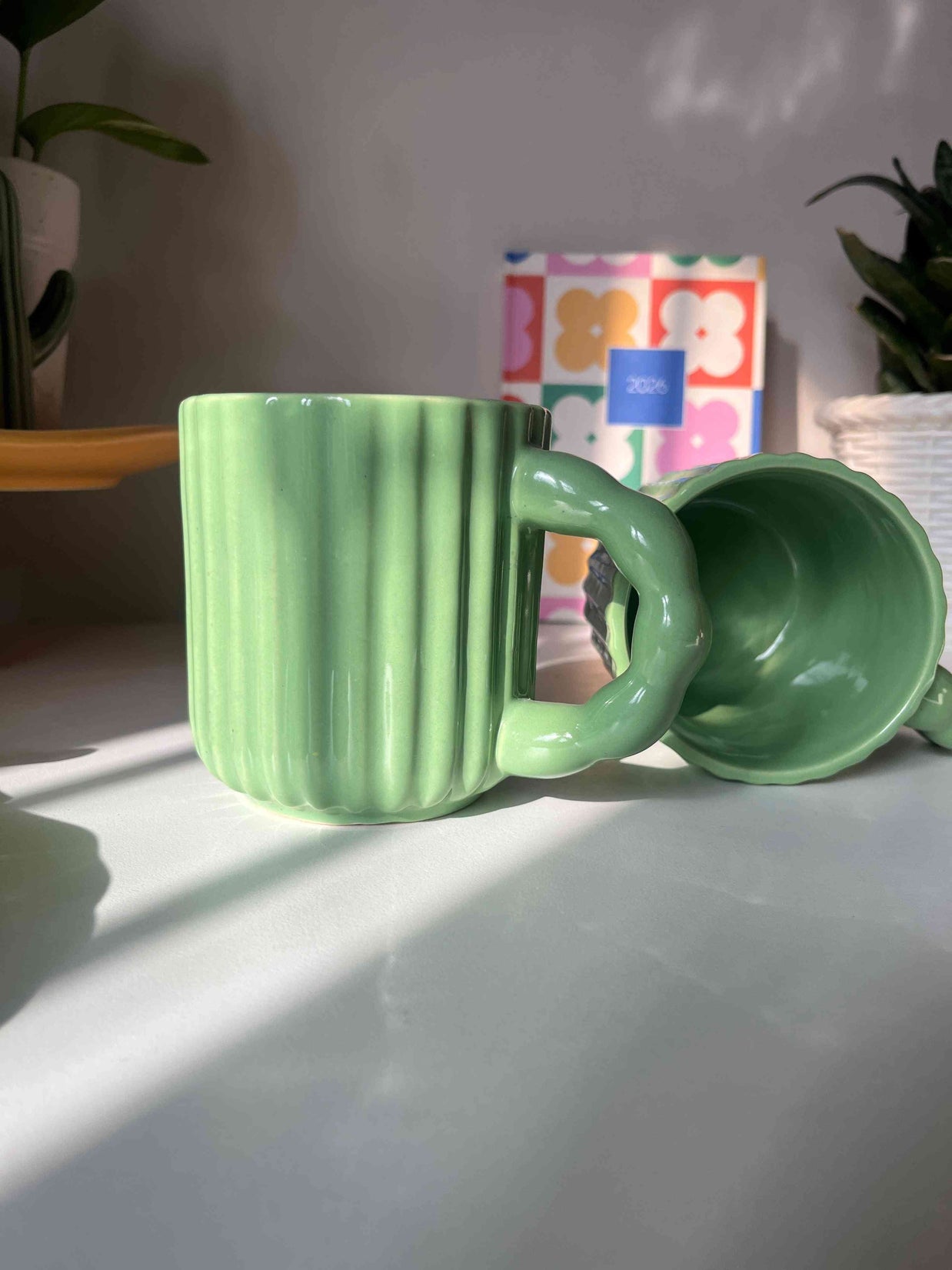 Close-up side view and top view of the ribbed ceramic texture and glossy green finish on the Kiwi Mug