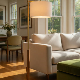 Living room with a white sofa, green ottoman, and standing lamp.