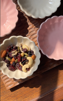 Small bowl of mixed nuts and dried fruits on a wooden surface with other bowls around.