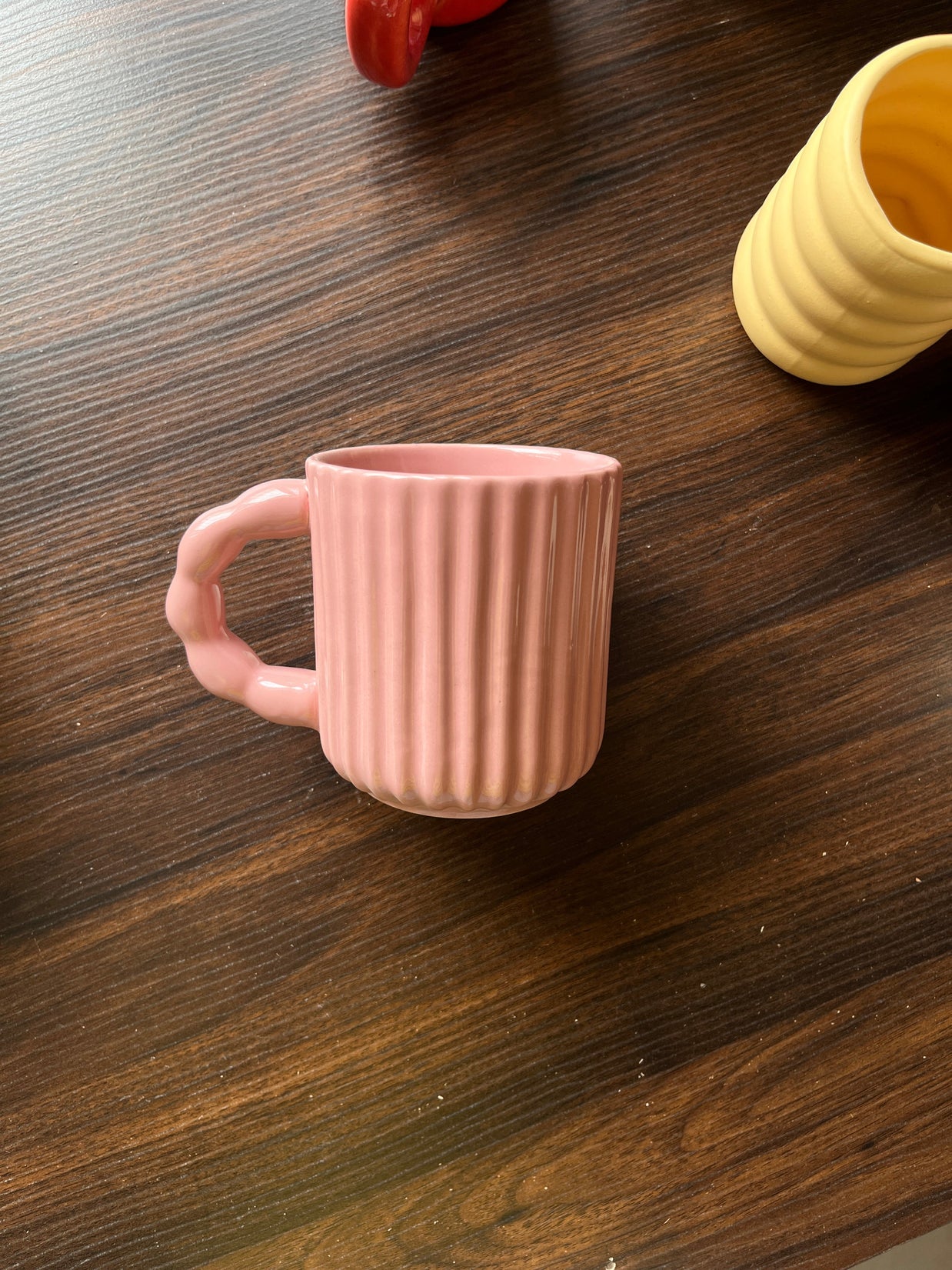 Side view of pink mug with ribbed texture on a wooden surface