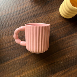 Side view of pink mug with ribbed texture on a wooden surface