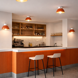 Modern kitchen with orange and white color scheme, featuring bar stools and a counter.