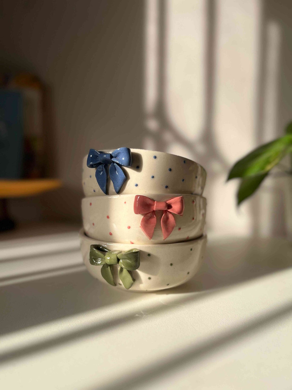 Three ceramic bowls with colorful bow decorations on a light surface.