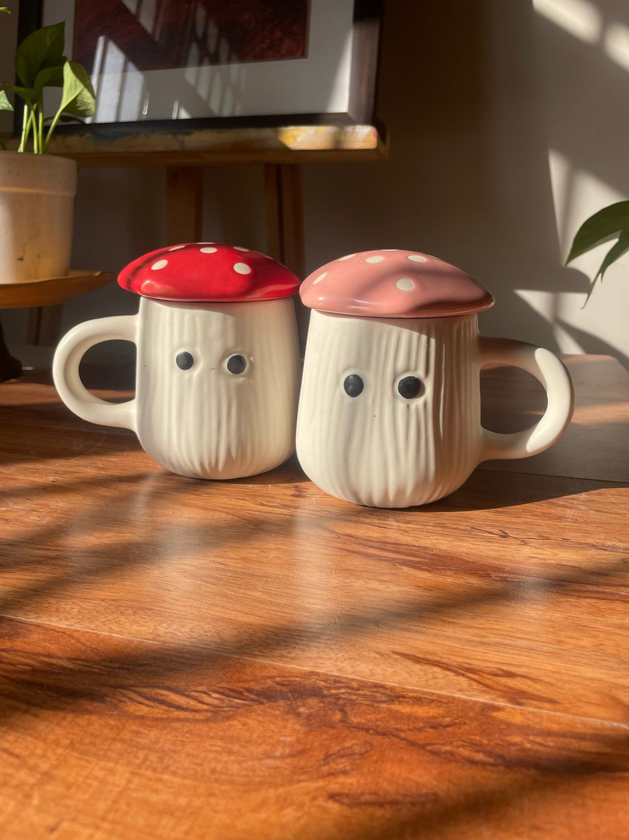 Two mushroom-shaped mugs with colorful caps on a wooden surface.
