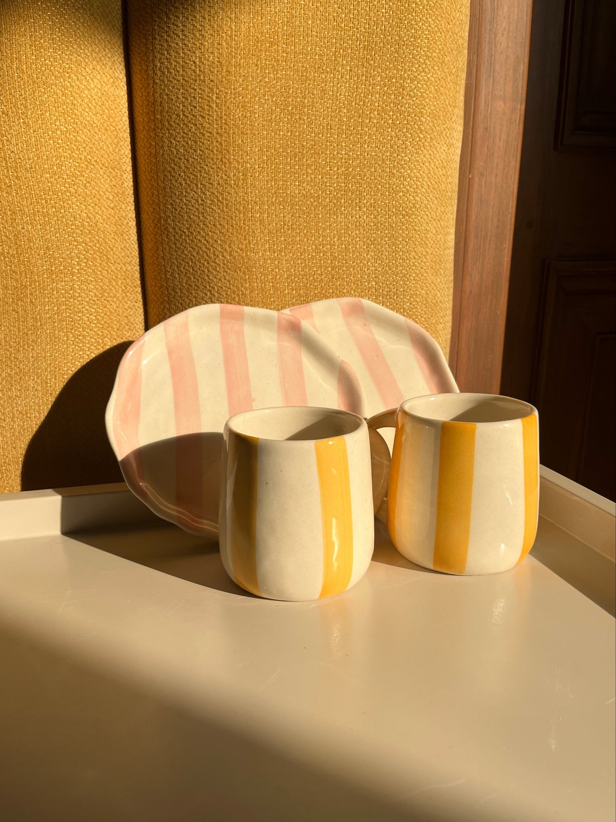 Close-up of the colourful ceramic mugs and plates from the Taffy Time set.