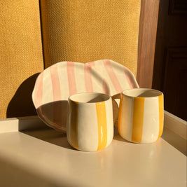 Close-up of the colourful ceramic mugs and plates from the Taffy Time set.