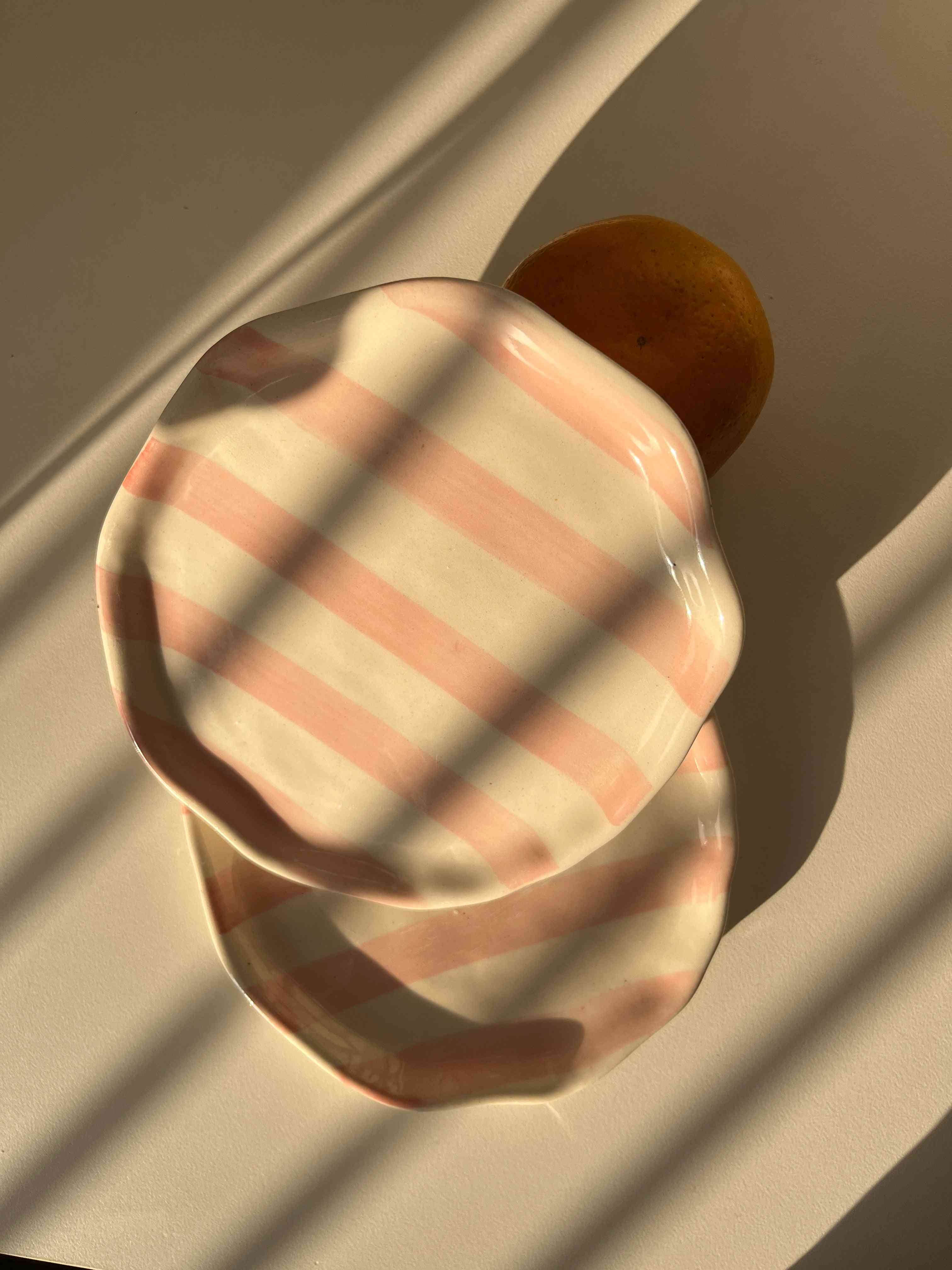 Pink striped ceramic plate on a textured surface