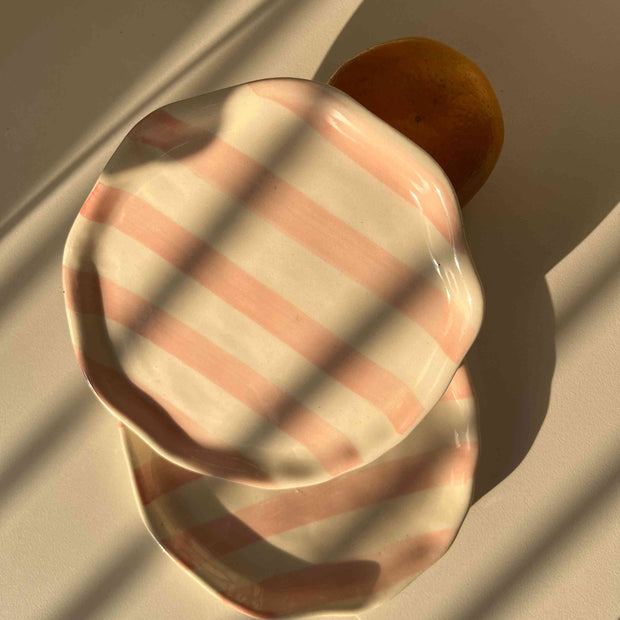 Pink striped ceramic plate on a textured surface